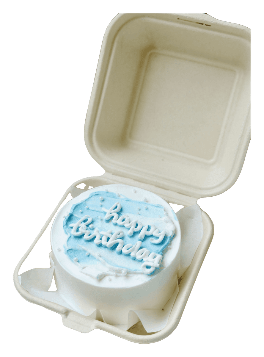 Mini bento cake piped with Happy Birthday in an open takeaway clamshell box