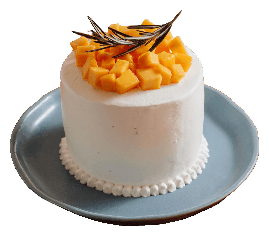 Mini white cake with a piped bead border, topped with fresh mango