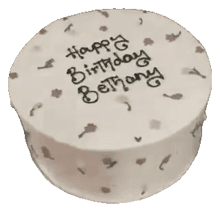 White round birthday cake with tiny piped pink flowers and a handwritten happy birthday message, made in Townsville